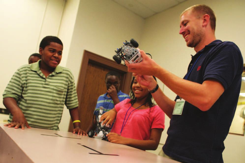 Campers watch as an instructor assists with a Lego robot programmed by a camper.
