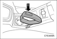 3. Nuleiskite svirtį žemyn laikydami įspaustą mygtuką. Saugokitės, kad automobilį statant ar važiuojant po juo nebūtų degių medžiagų.