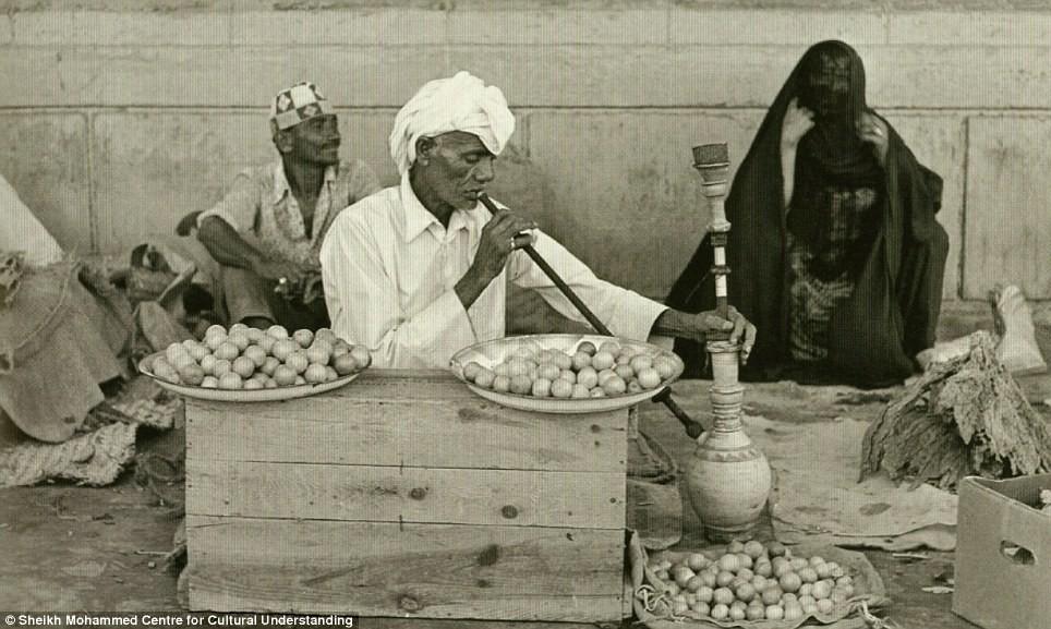 A man selling dried herbs and lemon pauses to smoke a shisha pipe: By 1892 foreign traders had begun to