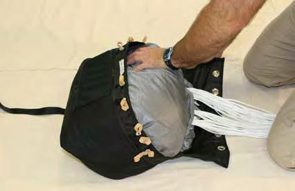 Begin placing the parachute into the main deployment bag (flap down) by placing one end of the parachute in the bag.