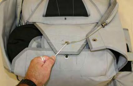 Hold the compressed pilot chute down with one knee, and then thread the pull-up cord through the grommet on the Flap-2. Figure 3.8.14.