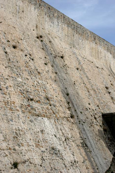 The dam has many serious problems: cracks, an eroding face with numerous holes, with one that penetrates through the dam and leaks.