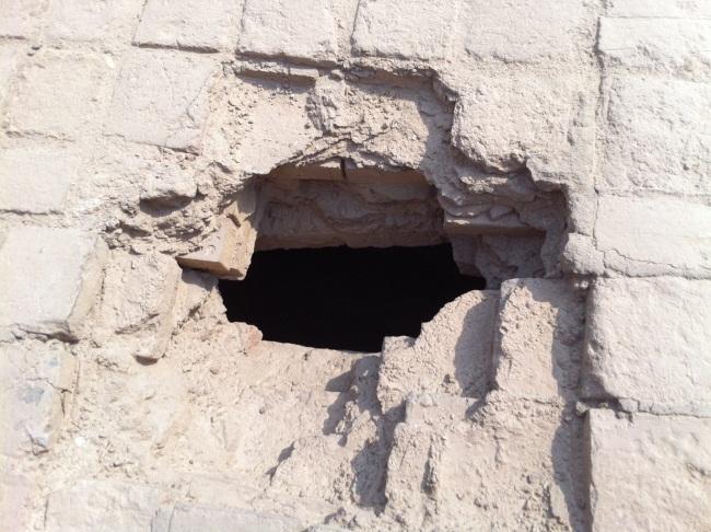 [Photo Caption: A manhole sized crack on the top of a wall at the Abbasid era Bab Al Wastani (The Middle Gate) in Baghdad. The hole was clearly used to penetrate the ancient wall.