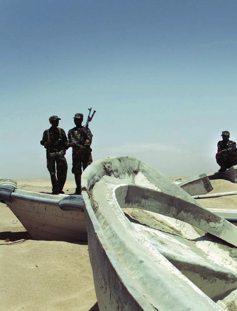Troubled Waters Somali Piracy 1 Pirate militiamen stand among fishing boats at