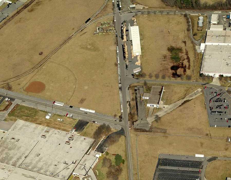 A circa 2006 aerial view looking north at the remains of 2 runways & the taxiway leading to the former ramp, now covered by an industrial building.