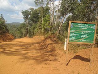 It shows a newly constructed road and a signboard from the Borderline Development Project, implemented by Burma/Myanmar Government [at the Kayin State level].