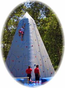 Safely monitored and carefully restrained from below, participants grab and step onto 'rocks' protruding from the Inflatable Rocky Mountain Climber Wall while edging