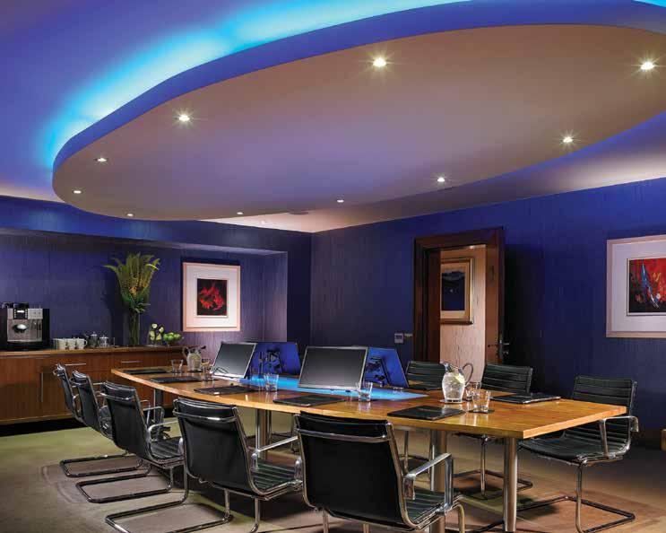 There is a fixed walnut boardroom table which can seat 12 people and a large wall mounted LCD television screen along with 4 smaller desk monitors fixed to the boardroom table which can relay what is