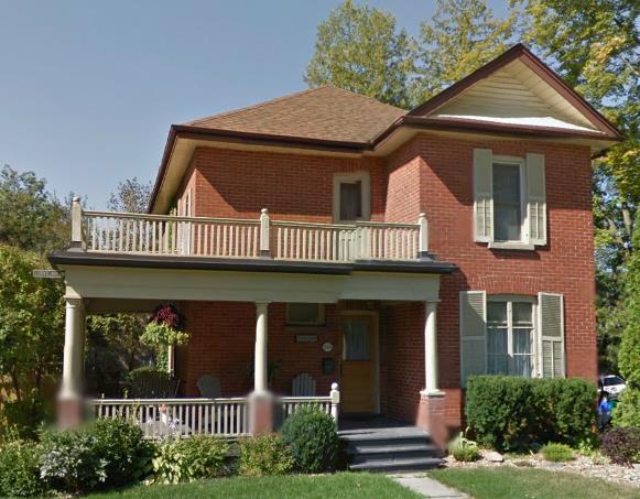 5-2-storey, red-brick house with a 1-storey veranda. - L-shaped floor plan. - Centred front door.
