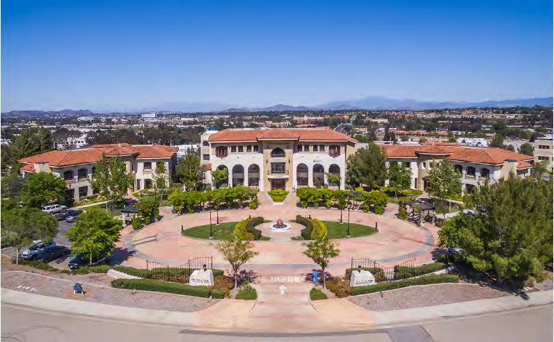 Serene park-like campus setting with lush landscaping, trellis-covered pathways, a beautiful water feature in a grand entry circular driveway, classic architecture and spectacular