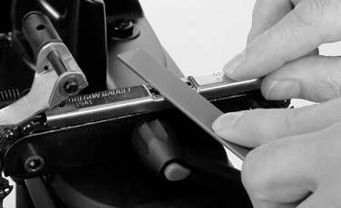 Coloque un Gaugit Oregon (herramienta para ajustar el medidor de profundidad) sobre la cadena en la prensa, sobre la parte del medidor de profundidad de la cuchilla (vea la